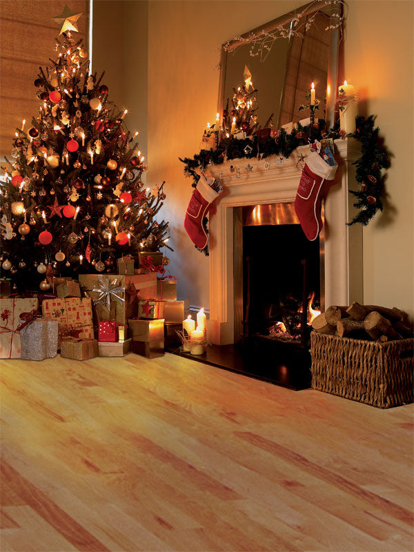 A warm Christmas backdrop featuring a decorated tree, glowing fireplace, stockings, and wrapped gifts.