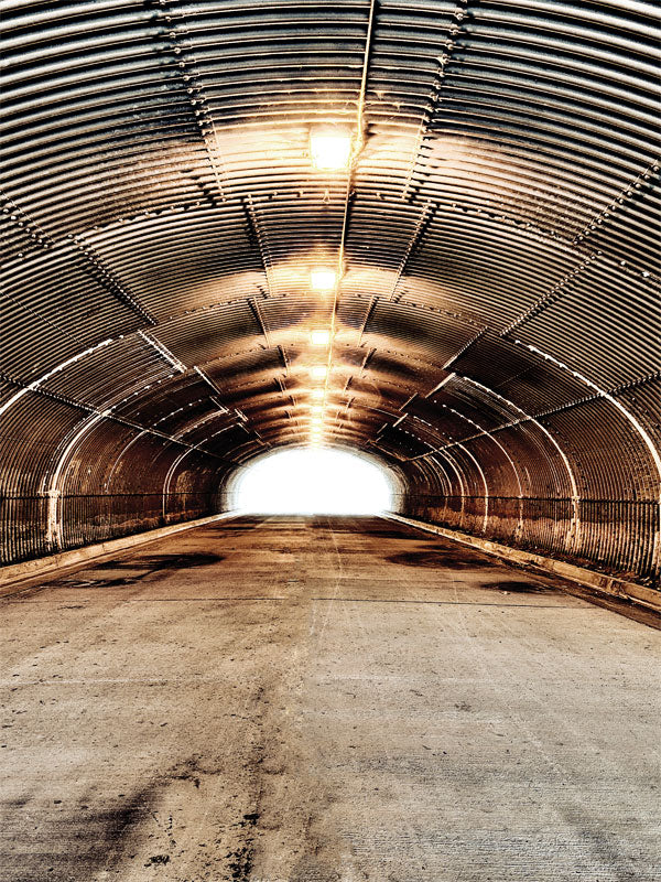 Industrial Elegance Photo Backdrop - Quonset hut tunnel with corrugated metal walls, warm central lighting, and a bright exit, creating an industrial and artistic ambiance.