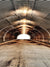 Industrial Elegance Photo Backdrop - Quonset hut tunnel with corrugated metal walls, warm central lighting, and a bright exit, creating an industrial and artistic ambiance.