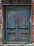 Distressed blue-green door photo backdrop with rustic brick.