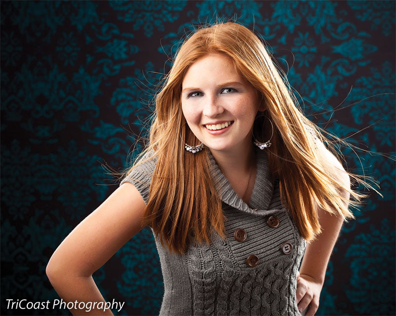 Dark studio backdrop with vibrant teal accents in a repeating damask style.