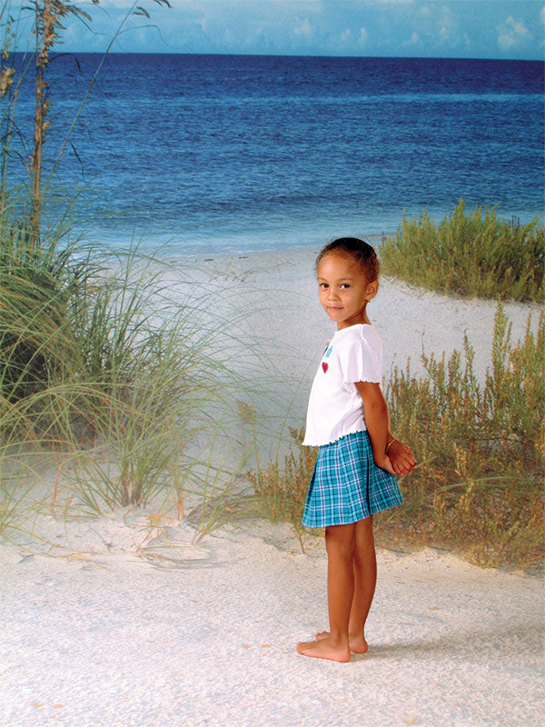 A scenic beach photography backdrop with deep blue ocean waves, white sand, and natural coastal grass, perfect for tropical-themed portraits.