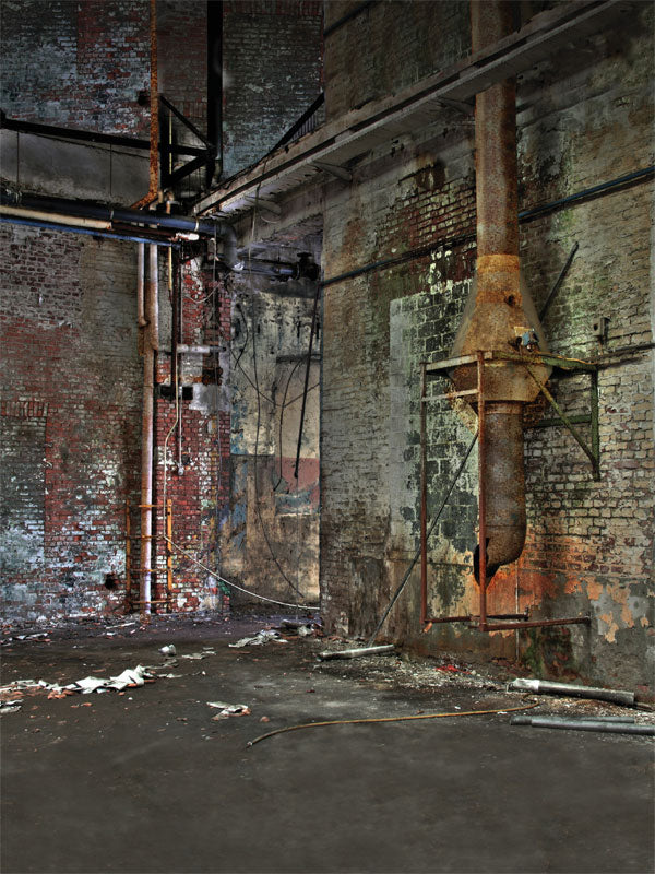 Weathered brick wall with rusted pipework in a vintage mill setting.