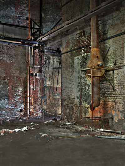 Weathered brick wall with rusted pipework in a vintage mill setting.