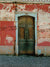 A rustic photography backdrop with a worn wooden door and distressed stucco wall.