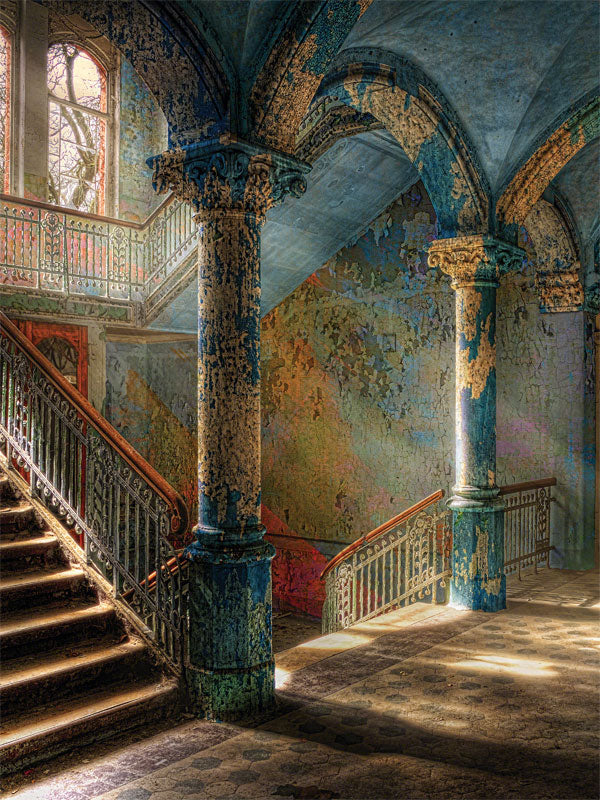 Grand staircase with peeling paint and vintage lighting.