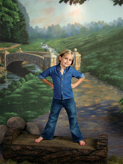 A countryside scene with a cobblestone bridge, winding path, and layered green landscape under soft morning light.