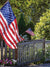 Patriotic Americana Photography Backdrop - Patriotic backdrop with American flags, wooden fence, and garden, perfect for photoshoots.