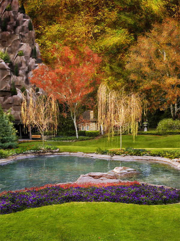A serene photography backdrop with a calm pond, golden willows, autumn trees, and a cozy garden cottage tucked in the background.