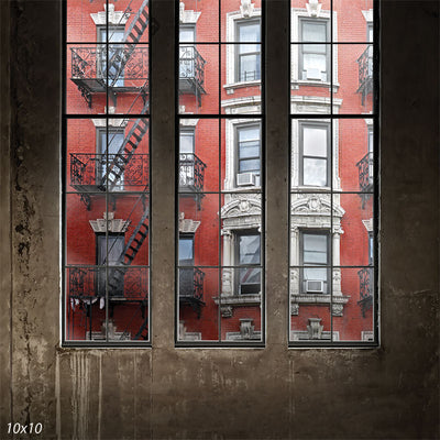Red brick apartment facade and fire escape framed by loft windows—ideal for senior portraits and urban studio photography.