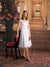 An opulent photography background with intricate carpet design, white columns, and vintage lighting.