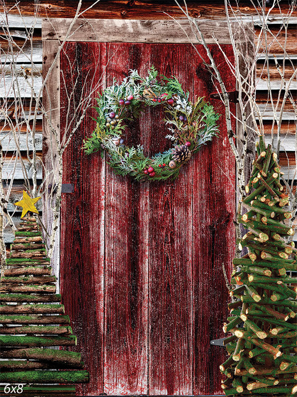 Rustic Christmas Barn Door Photography Backdrop - Photography backdrop featuring a red barn door with a Christmas wreath, flanked by rustic log Christmas trees.