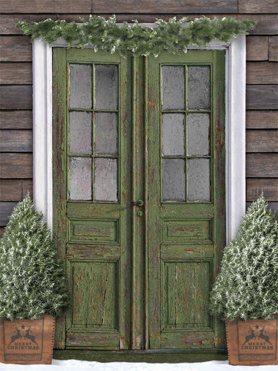 Rustic Christmas Door Photography Backdrop - Photography backdrop featuring a rustic green door decorated with evergreen garland and frosted Christmas trees, ideal for holiday portraits.