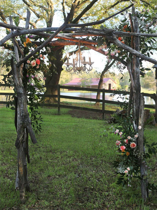 Rustic Garden Wedding Arch Photography Backdrop - Rustic garden wedding arch with flowers and chandelier in a woodland setting, ideal for romantic or nature-themed photography.