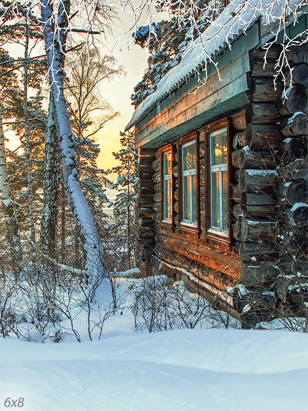 Rustic Winter Cabin Photography Backdrop - Photography backdrop featuring a cozy log cabin in a snow-covered forest at sunset, with warm lights glowing from the windows.