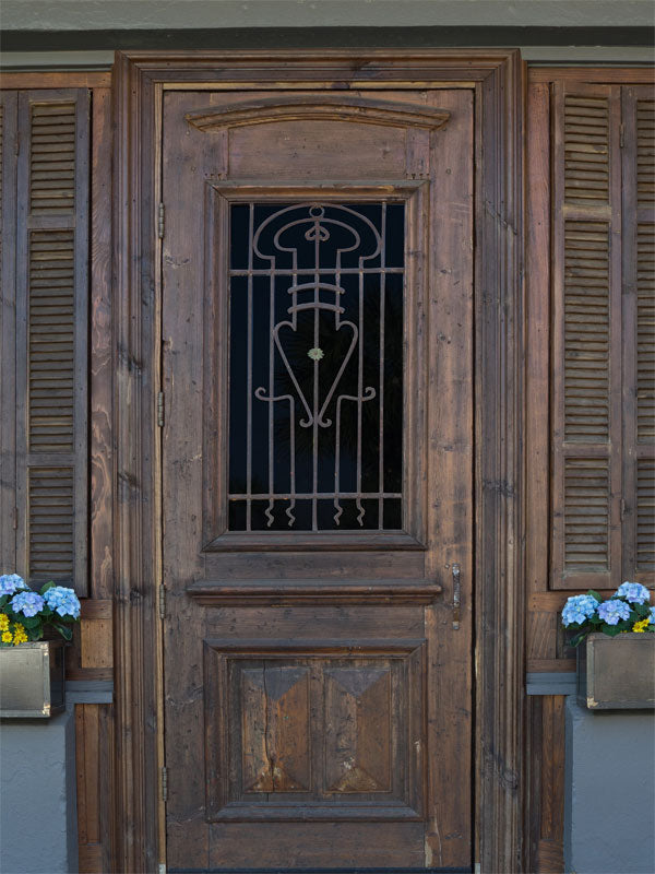 Rustic Wooden Door Photography Backdrop - Photography backdrop featuring a rustic wooden door with intricate iron detailing and framed by matching shutters, perfect for vintage and rustic-themed photoshoots.