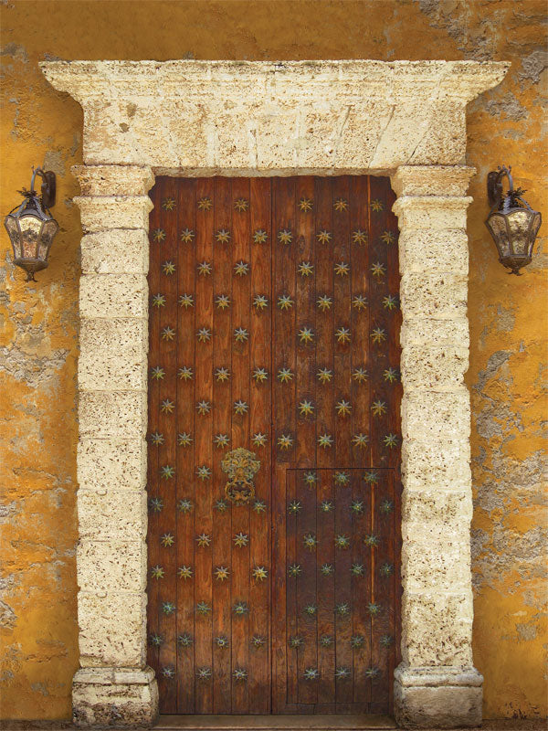 Antique colonial door with brass studs and weathered texture in warm tones.