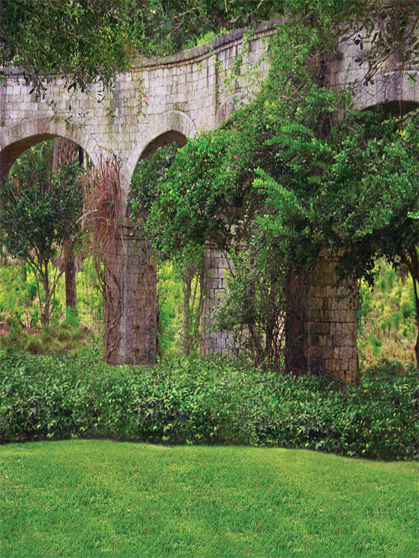 A rustic stone courtyard photography backdrop featuring elegant arches, aged brick, and lush greenery, perfect for vintage and wedding-themed portraits.