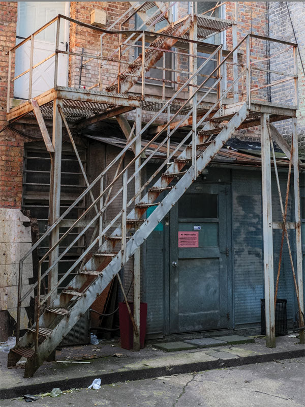 Rusty Industrial Fire Escape Photography Backdrop - A gritty industrial photography backdrop featuring a rusted fire escape and worn brick walls, perfect for urban-themed photoshoots.