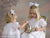 Two girls dressed in white lace gowns host a tea party against a dreamy, floral backdrop—suitable for vintage-style children’s portraits.