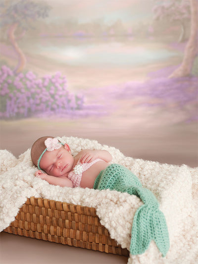 Newborn baby sleeps peacefully in a mermaid costume with a dreamy, pastel Sheffield garden scene behind, perfect for whimsical newborn photography sessions.