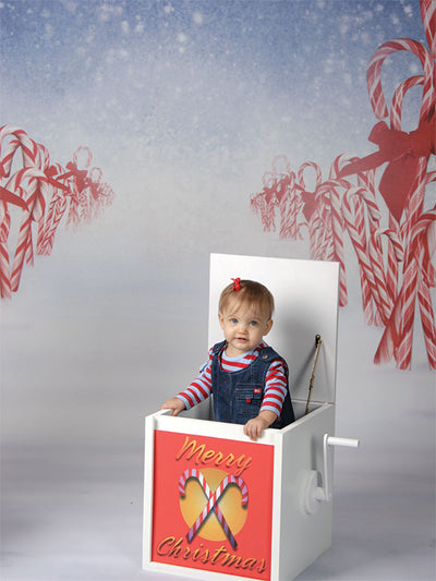 A magical holiday backdrop featuring candy canes, soft snow, and a dark blue gradient sky with flurries.