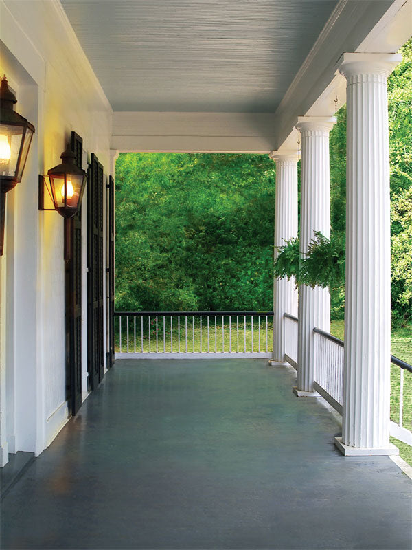 A classic Southern-style porch photography backdrop with white columns, warm lantern lighting, and lush greenery, perfect for vintage and bridal portraits.