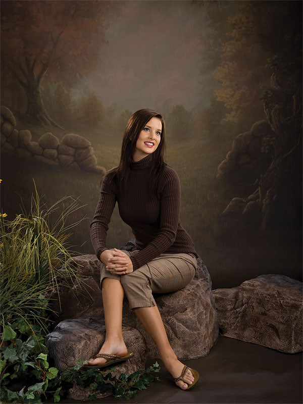 Peaceful forest edge with weathered tree, stone wall, and soft natural light.