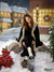 Cozy Christmas backdrop with warm yellow window light and red bows.