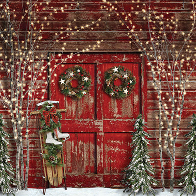 Photography backdrop featuring a rustic red barn door decorated with holiday wreaths and twinkling lights, perfect for winter portraits.