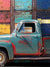 Vintage Truck with Colorful Garage Door Backdrop - Photography backdrop featuring a teal-colored vintage truck in front of a weathered, multicolored garage door.