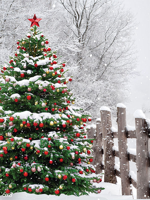 Winter Wonderland Christmas Tree Photography Backdrop - A serene winter photography backdrop featuring a snow-covered Christmas tree adorned with colorful ornaments, set in a snowy landscape with a rustic wooden fence.