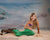 Child in mermaid costume posed in front of an ocean backdrop with beach props, ideal for creative dance or themed portrait sessions.