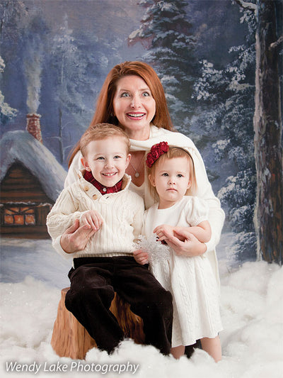 A heartwarming family session in front of a glowing cabin and snow-covered trees, perfect for holiday cards and winter portraits.