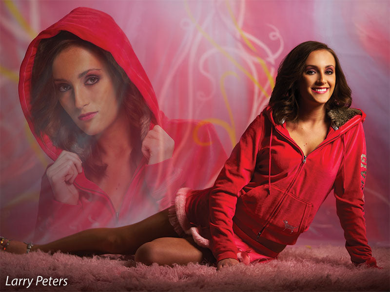 Senior girl with dual exposure effect posed in red hoodie on vibrant pink gift wrap-style photography backdrop.