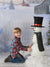 A young boy smiles beside a snowman in front of the printed snowy Country Holiday backdrop, perfect for seasonal studio photos.
