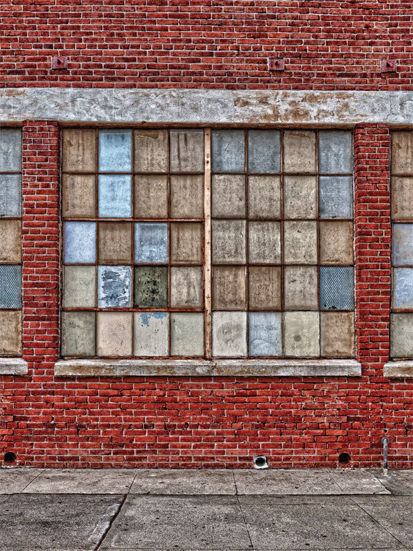 Rustic red brick wall with large, weathered industrial windows, perfect for urban and portrait photoshoots.