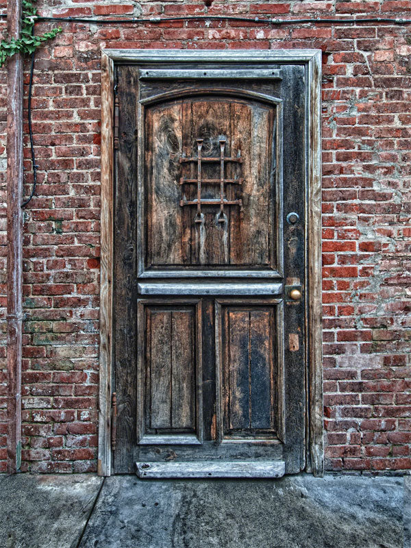 Rustic wooden door set against a red brick wall, perfect for adding a vintage and textured look to portrait photoshoots.