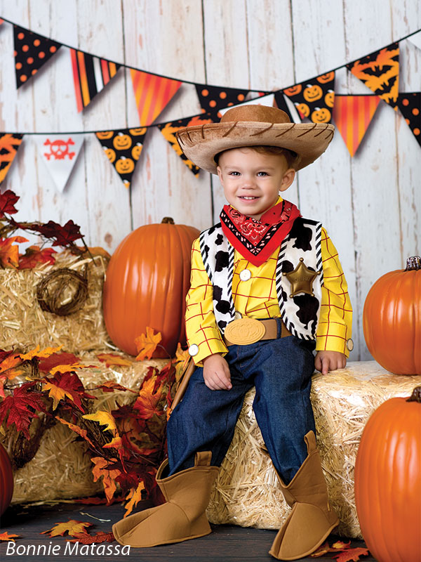 white wood wall backdrop with toy story costume pumpkins hay