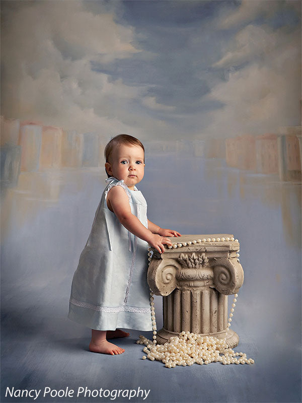 Portrait of baby with vintage column and pearls in front of romantic city waterway backdrop, ideal for newborn or milestone shoots.