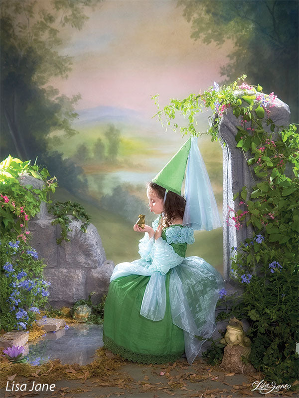 Printed landscape backdrop with distant hills and morning light, featured in a styled session with a young model in a princess dress and cone hat.