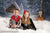 Two children pose in front of the Holiday Cottage backdrop, surrounded by snowy textures and a glowing winter forest scene.