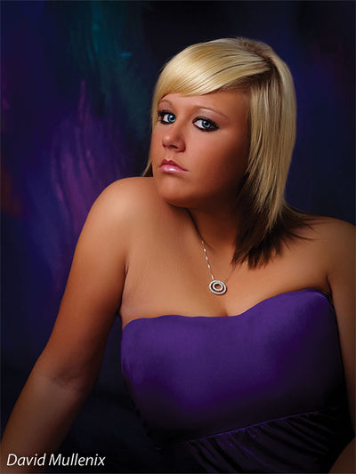 Teen girl poses confidently in front of a dramatic multicolor abstract backdrop, perfect for senior sessions with artistic flair.
