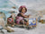 Smiling infant in playful seaside setup with waves and rustic beach props, ideal for newborn and toddler portrait sessions.