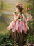 Printed photography backdrop with soft green landscape and whimsical charm, styled with a child model in fairy wings kissing a frog prop.