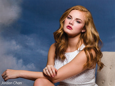 Close-up senior portrait with dreamy blue and gold waterway backdrop, ideal for school, dance, or editorial photography.