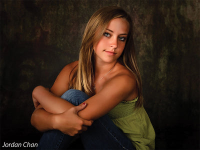 Model seated in front of the Scrolled Backdrop, demonstrating how the muted scroll elements and textured finish enhance fine art portraiture.