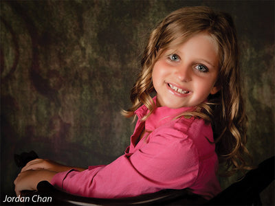 Model seated in front of the Scrolled Photography Backdrop, highlighting its classical scroll pattern and moody earth tones for heritage-style portraits.