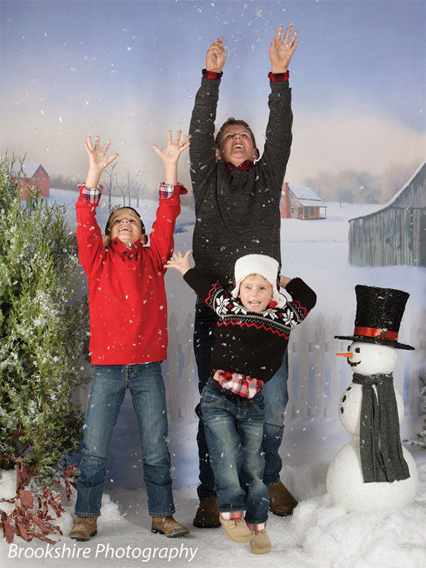 Three boys celebrate winter fun in front of a Christmas farm backdrop complete with snow and festive cheer.