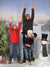 Three boys celebrate winter fun in front of a Christmas farm backdrop complete with snow and festive cheer.